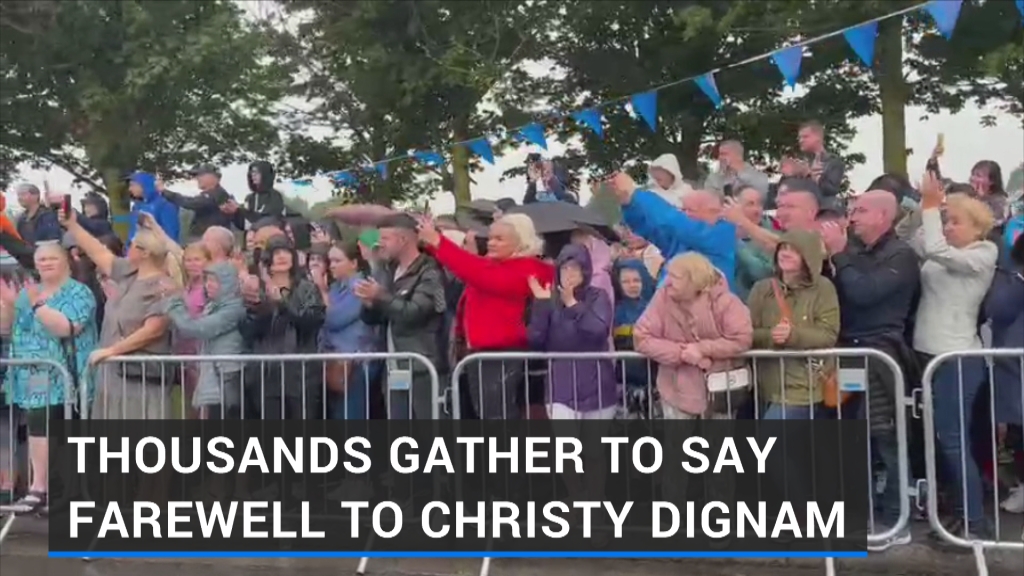 Thousands of Aslan fans sing as Christy Dignam's family pause to watch a video tribute to him in Finglas as part of his funeral procession | Read more: