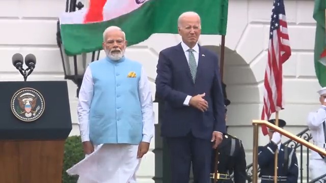 Biden, alongside Indian Prime Minister Narendra Modi, slowly lowers his hand from his heart after realizing they're playing the Indian national anthem first