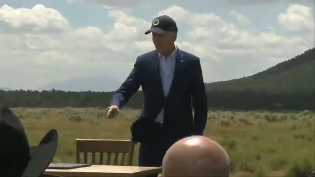 A confused Joe Biden salutes the audience and meanders off stage