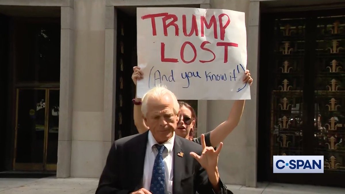 After a judge ruled against him in his criminal contempt case, former Trump advisor Peter Navarro attempts to snatch a "Trump lost" sign from a protester at his press conference.