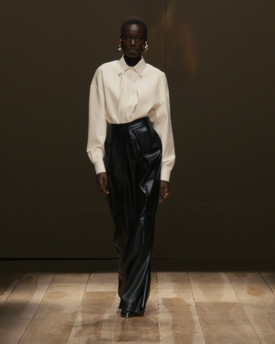 A #McQueenAW23 ivory drop shoulder folded shirt and black folded trousers. Discover the collection: