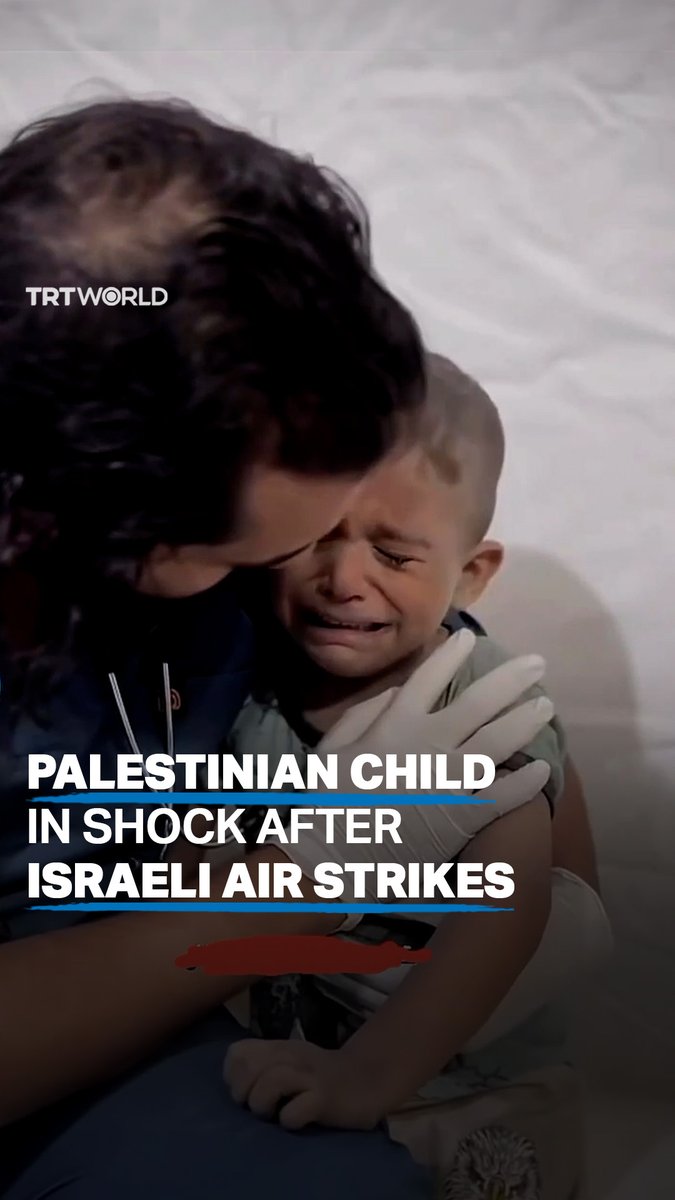 A Palestinian child named Mohammed appears to be in a state of shock as he is comforted by a man after having woken up to the sounds of Israeli air strikes