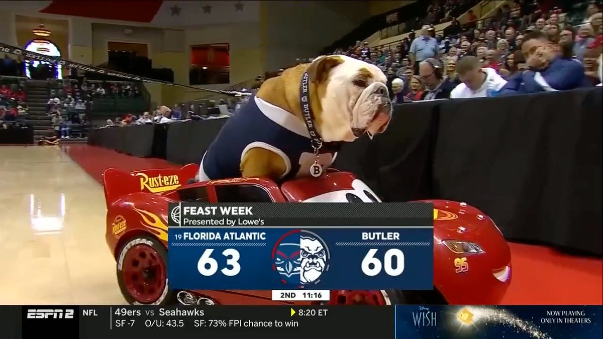 Isso aqui é o basquete universitário O cachorro mascote de uma universidade andando de Relâmpago McQueen durante uma pausa no jogo Ninguém tá puro