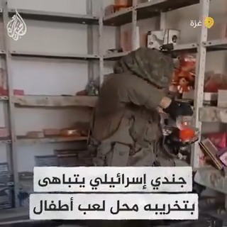 جندي إسرائيلي يسخر من الفلسطينيين أثناء اقتحامه وتخريبه أحد محلات لعب الأطفال في مخيم جباليا بقطاع غزة بعد أن اجتاحته القوات الإسرائيلية