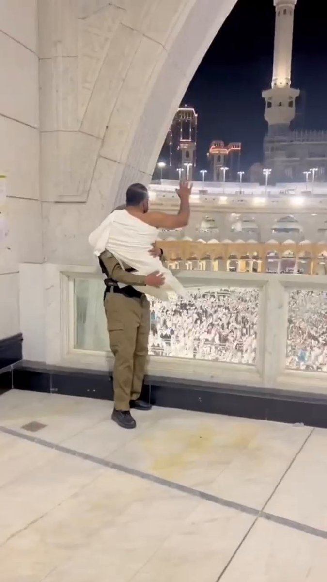رجل أمن يحمل معتمرًا من ذوي الإعاقة ليشاهد #الكعبة🕋.