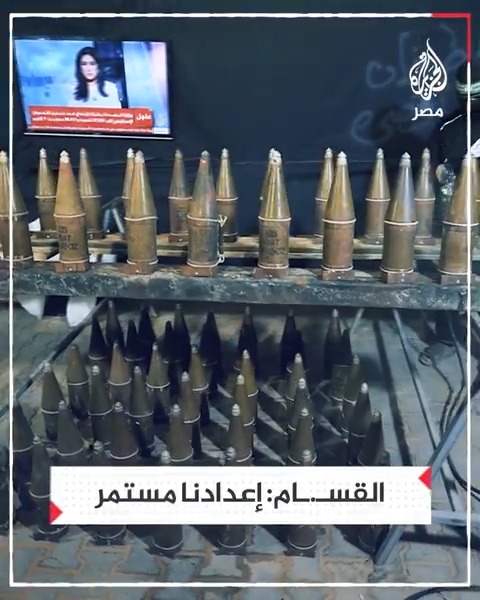 كتـ.ـائب القسـ.ـام تبث مشاهد تظهر استمرار عمليات التصنيع والإعداد الحربي وفي الخلفية شاشة الجزيرة وهي تعرض أخبار الأسبوع الماضي