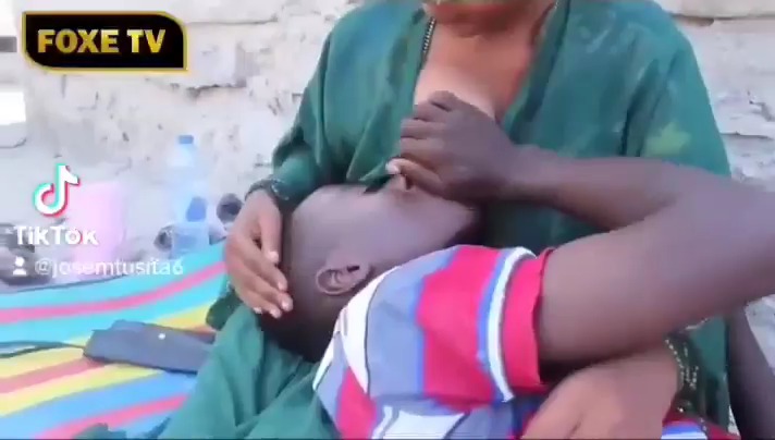 How is this Tanzanian mother still breastfeeding her 17 year old son?Just look at how she's rubbing his head, what is she thinking?