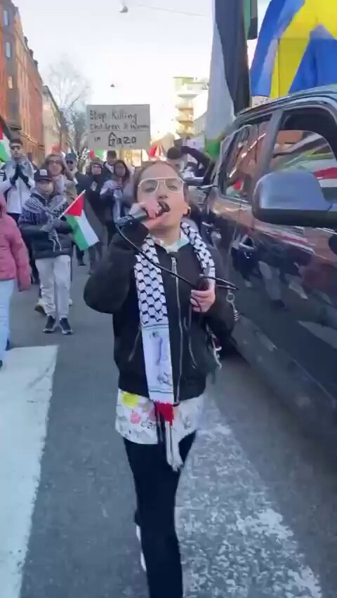 Bir kız, İsveç'in başkenti Stockholm'de Filistin'e destek gösterisine öncülük ediyor.