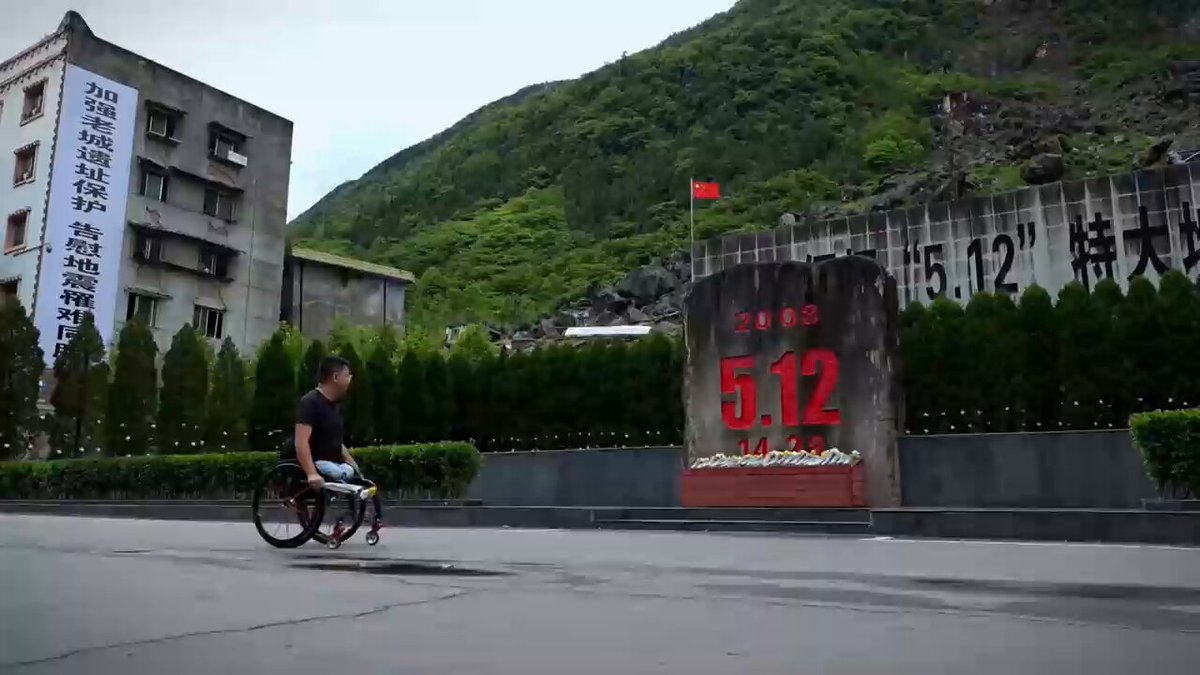 汶川地震幸存者重回故地，为遇难的他们捧上一束花。