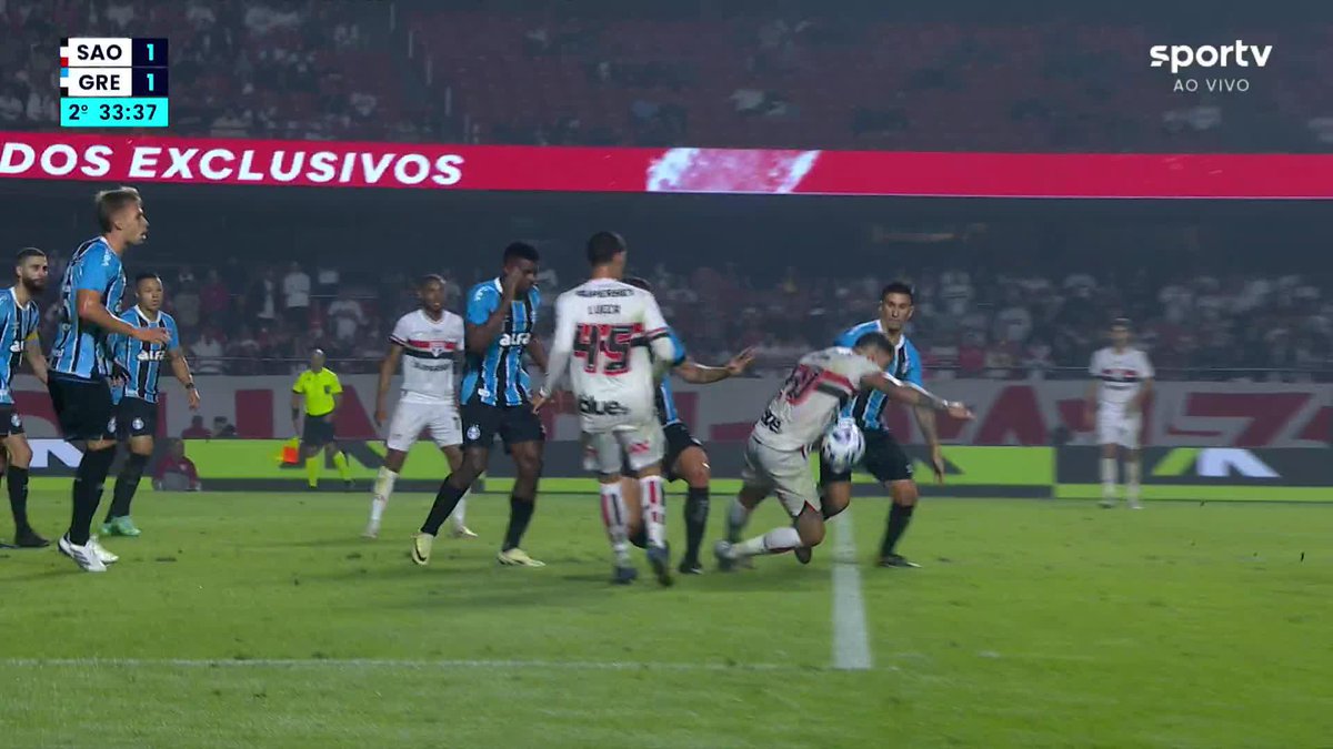Luciano é derrubado por Camilo dentro da área, e a arbitragem assinala pênalti para o São Paulo. Jogadores do Grêmio reclamam muito.