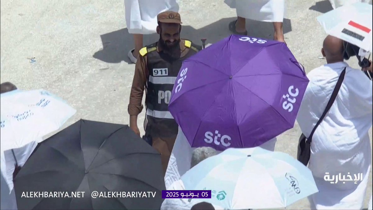 Despite the high temperature, a smile is on his face. A security man cools the atmosphere for pilgrims with a spray bottle.