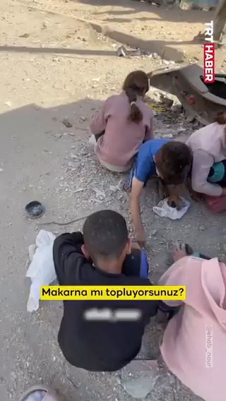 Katil İsrail'in açlığa mahkum ettiği Gazze'de, yerden bir avuç makarna toplayan Filistinli çocuklar...