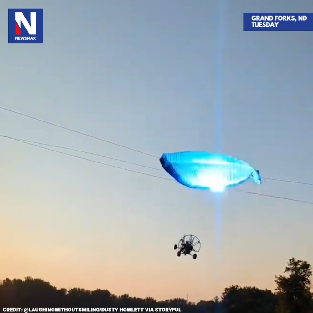 SHOCKING MOMENT: A paraglider collided with a power line and fell into a river in Grand Forks, North Dakota, on Tuesday, in a terrifying incident caught on camera. Miraculously, the pilot escaped without injury, according to reports.