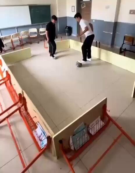 2 liseli genç, sıralardan saha oluşturup sınıf içinde maç yaptı.