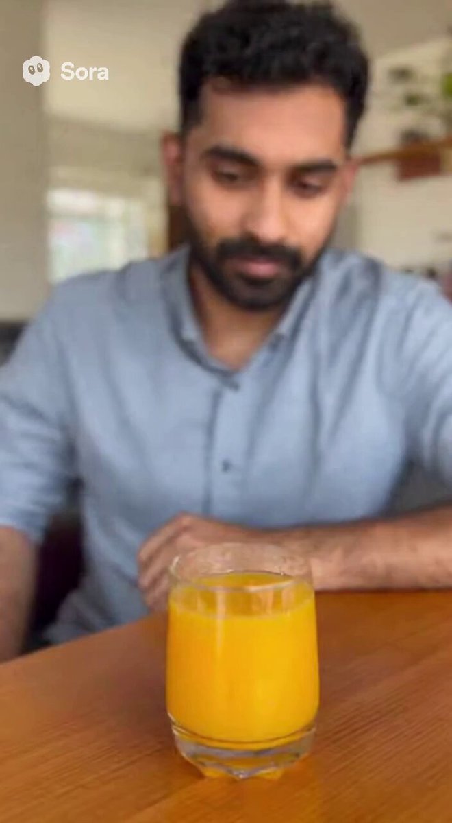 “The scene begins with a man sitting at a table. There is a small glass of orange juice on the table. He picks up the glass, drinks all of the orange juice, and places the empty glass back down on the table.”