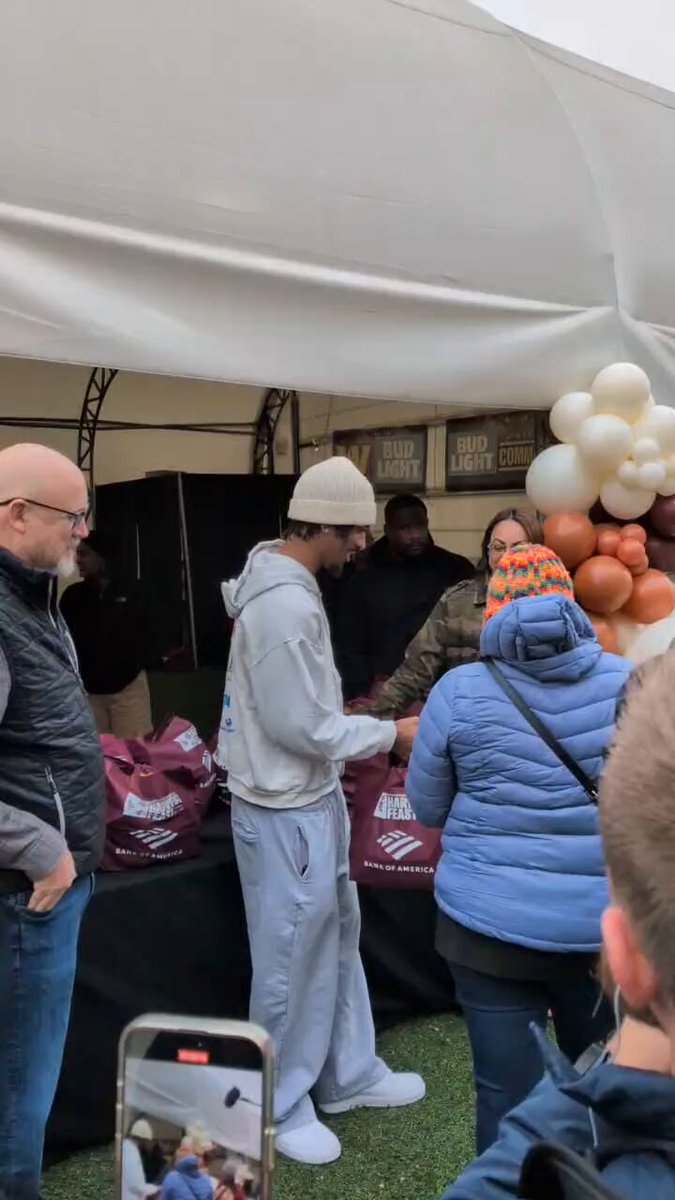 Jayden Daniels handing out bags of food to members of the community (with his right arm only)