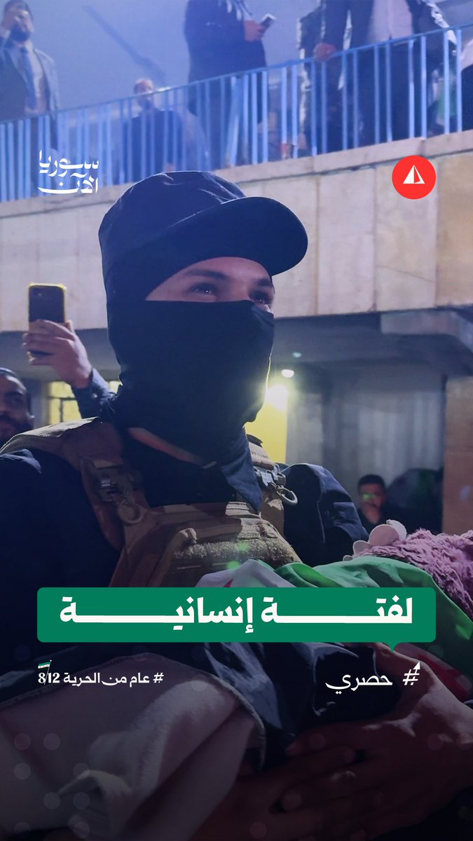 رجل أمن يحمل طفلة نائمة دون أن ينسى مهمته في احتفالات دير الزور