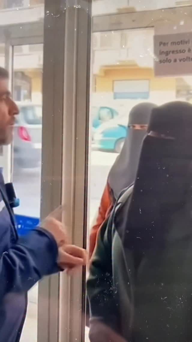 A security guard gives the women in burqas two options: uncover your faces or leave