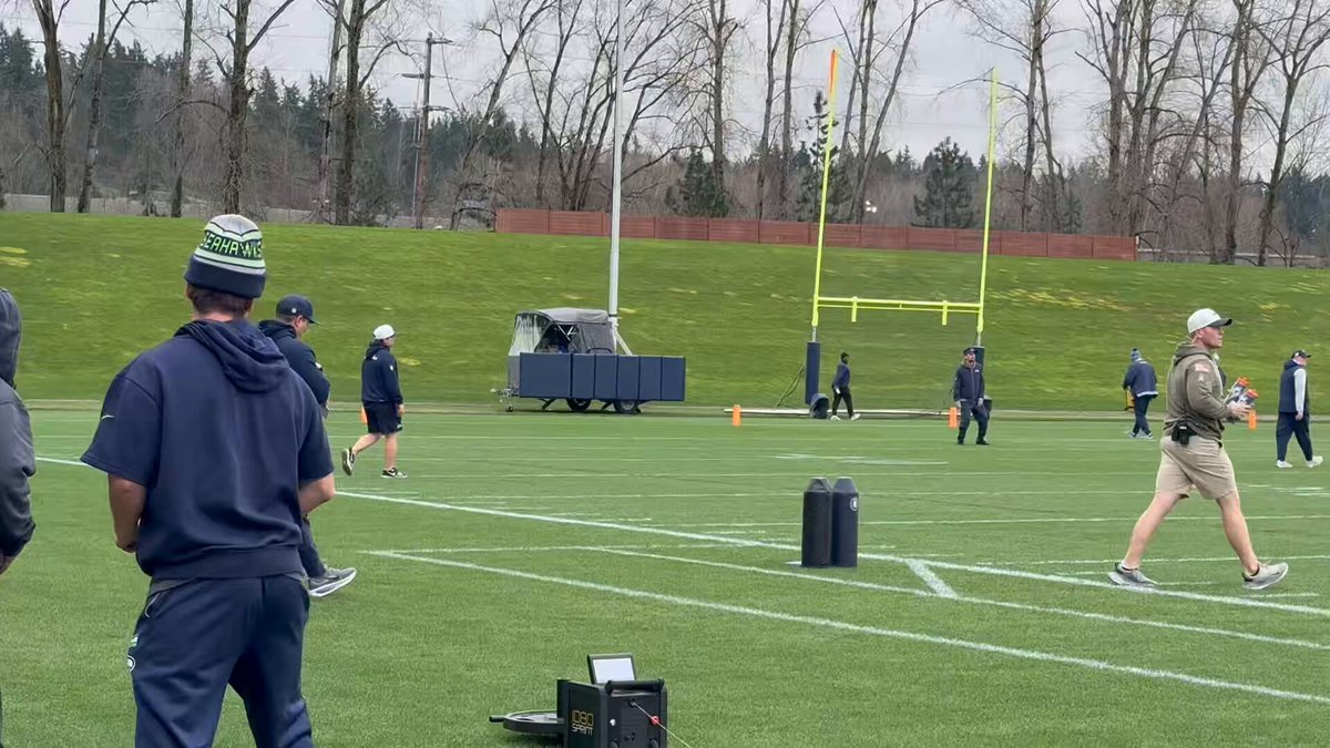 Mike Macdonald makes his way onto the practice field as AJ Barner gives him a welcome tap