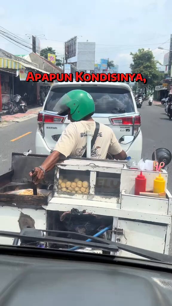 Apapun kondisinya, gorenganku tetap yang utama ‼️ Terlihat momen si abang jualan tetap sibuk dengan dagangannya diatas motor walau suasana macet begini. Gorengan tetap nyala dan tetap diaduk supaya matang merata.