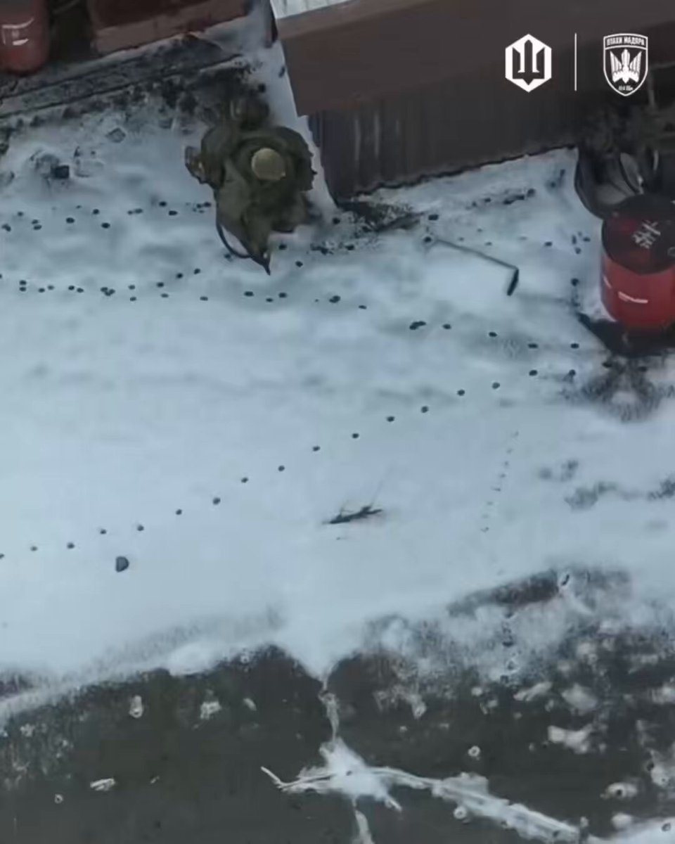 A Russian infantryman is taking cover inside a hangar filled with red barrels.
