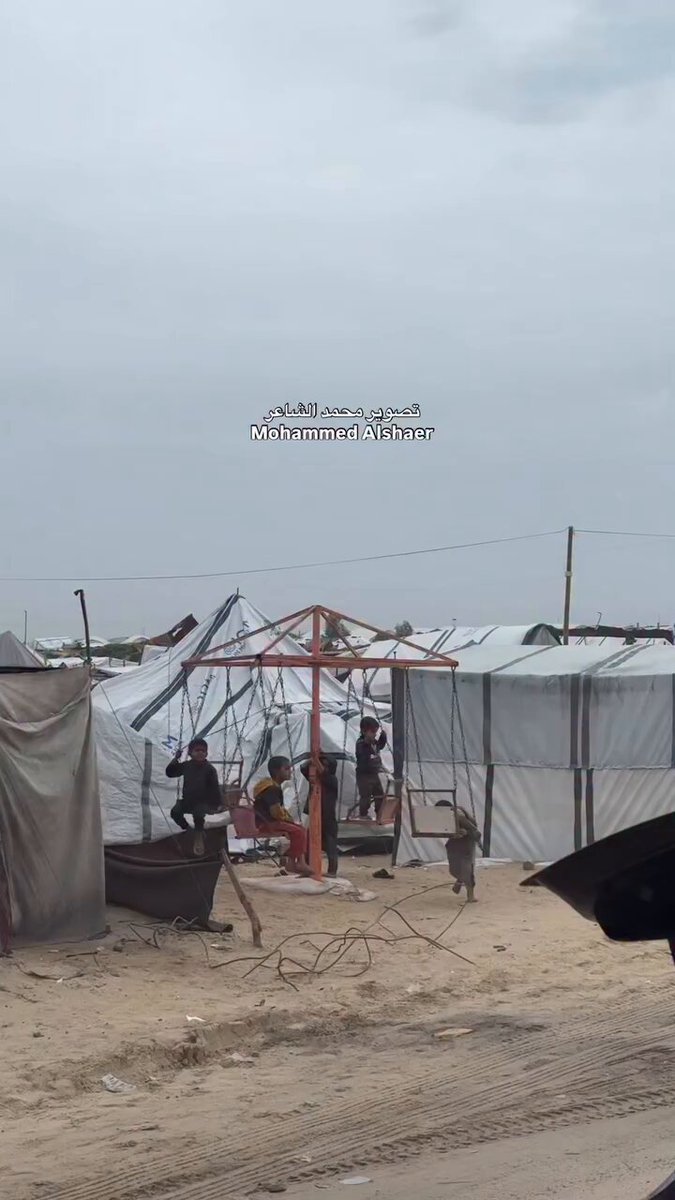 تُظهر الصورة مشاهد من حياة أطفال في غزة، يعيشون بين خيام مهترئة وظروف إنسانية قاسية، حيث يحاولون التمسك بلحظات لعب بسيطة وسط واقع يثقل كاهلهم، وأمل بالحياة.