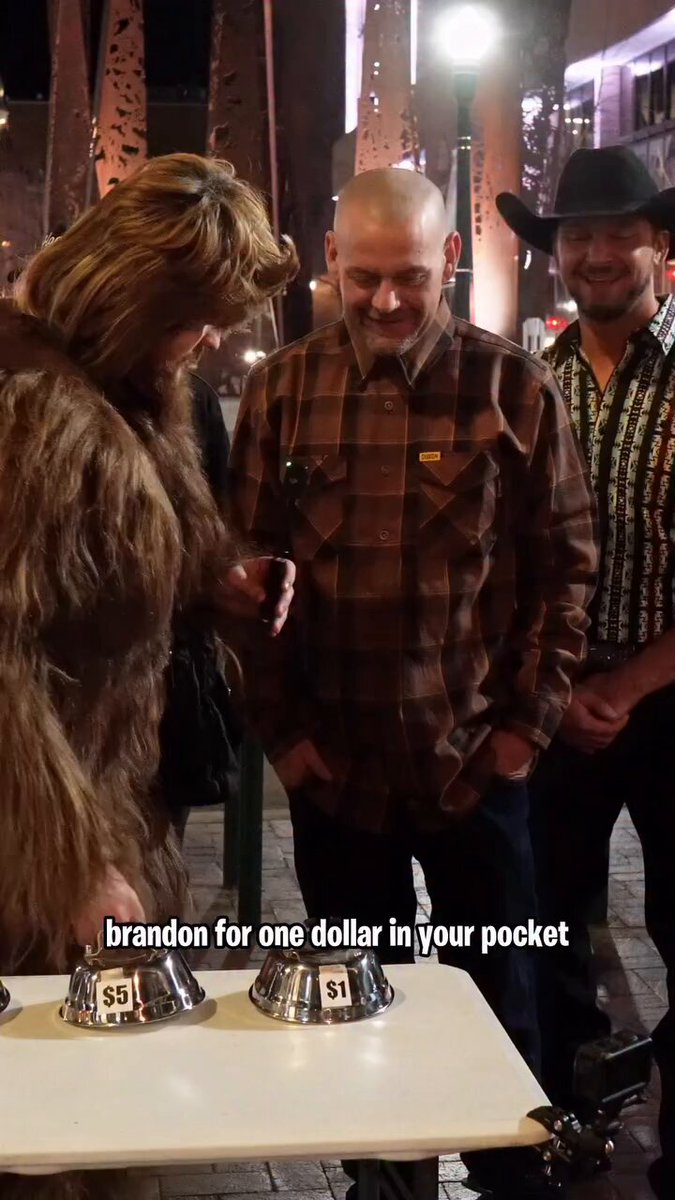 A guy in a Bigfoot costume is offering strangers $10 to eat a live cricket and $20 to eat a live earthworm. One dude accepts every single challenge and eats every bug without flinching.