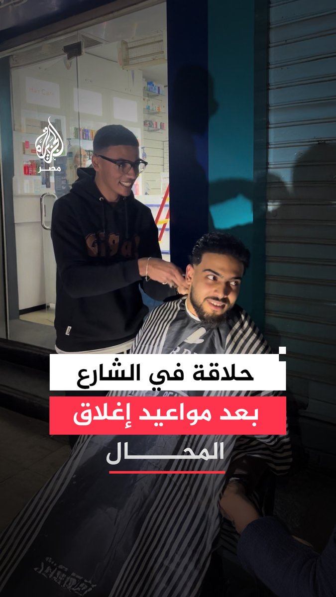 مشهد فكاهي لحلاق يقص شعر أحد زبائنه على الرصيف في أحد شوارع الإسكندرية بعد مواعيد الإغلاق المبكر.. كيف تفاعل المارة مع المشهد؟