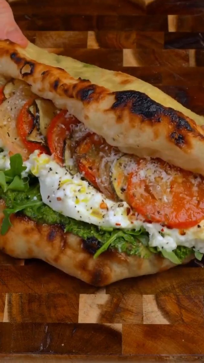 Pizza Sandwich from Yarin Danieli 🔥 🍕 Fresh-baked dough stuffed with basil pesto, roasted veggies, peppery arugula, and creamy burrata. Save for later 🔖