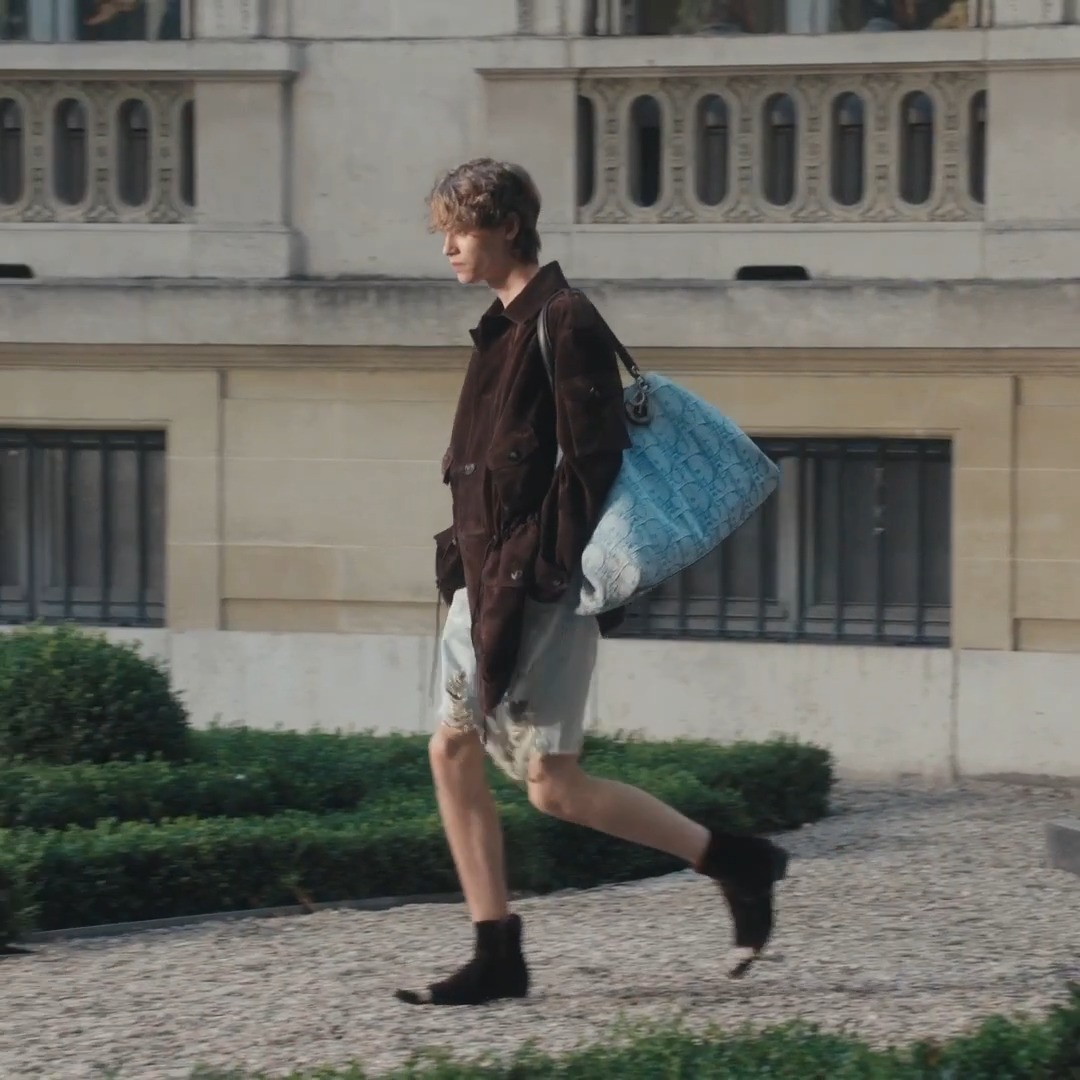 Dior Summer 2027 Men's Show. A loosening of dress codes rooted in juxtaposition: the precise meets the relaxed, softened tailoring segues into fringe, crisp shirts pair with bouclé denim, deliberately distressed surfaces are created with couture-like embroidery.