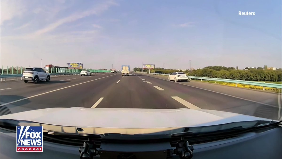 A driver narrowly avoided disaster after a tarp flew off a truck and completely covered the windshield of a moving car on a highway in Xinjiang, China. With visibility instantly reduced to zero, the driver kept calm, switched on the hazard lights, gradually slowed the vehicle, and safely pulled onto the shoulder instead of making a sudden maneuver. After stopping, the tarp was removed from the windshield. No one was injured, and the incident ended without a crash.