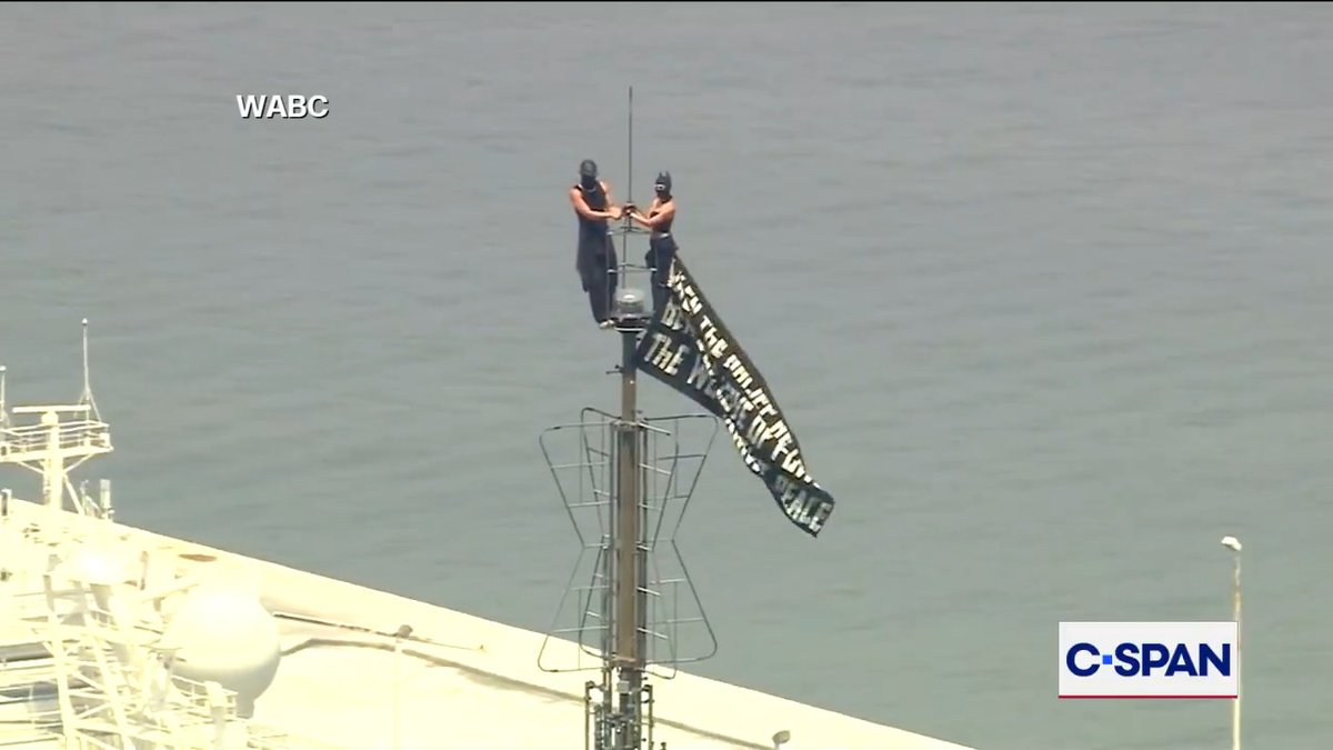 Masked protesters fly banner atop Empire State Building. The banner reads: When the power of love Beats the love of power The world knows peace Watch more here:
