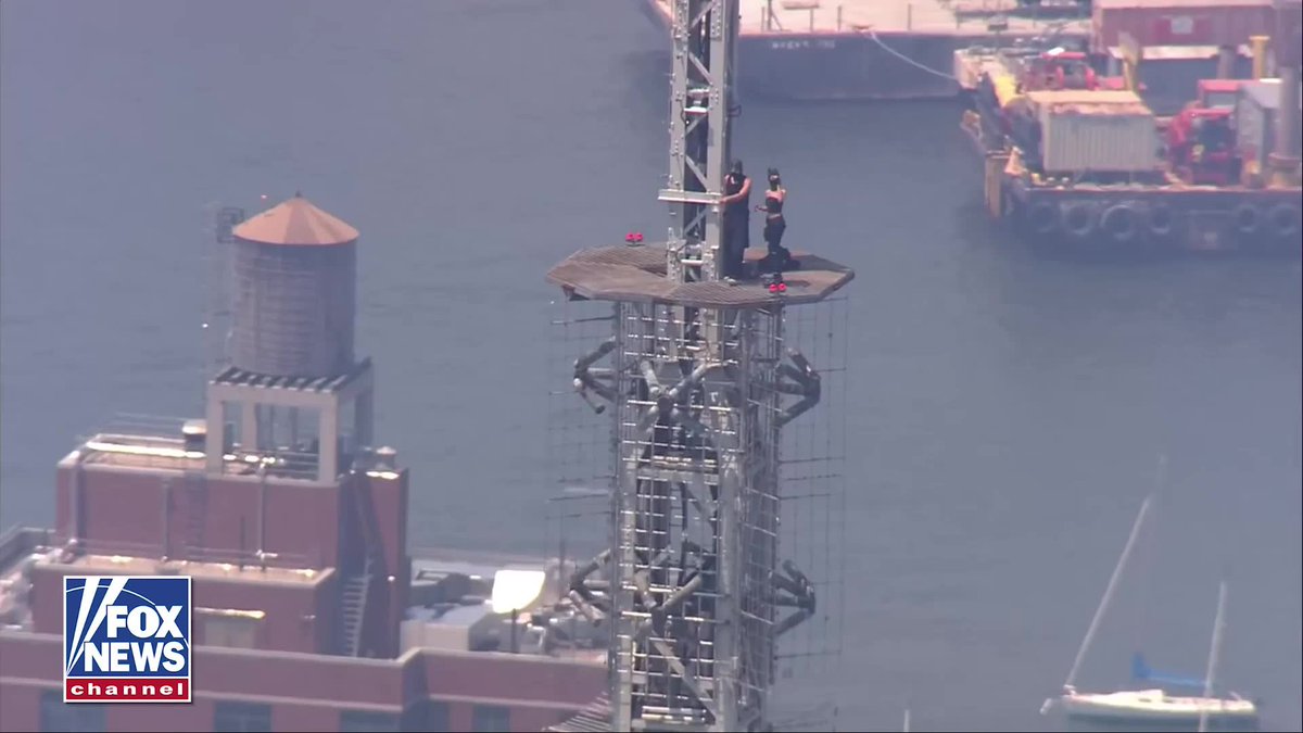 BREAKING: Man appears to propose to woman at the top of the Empire State Building. The pair were earlier seen climbing the spire and holding a banner reading, "When the power of love beats the love of power, the world knows peace."