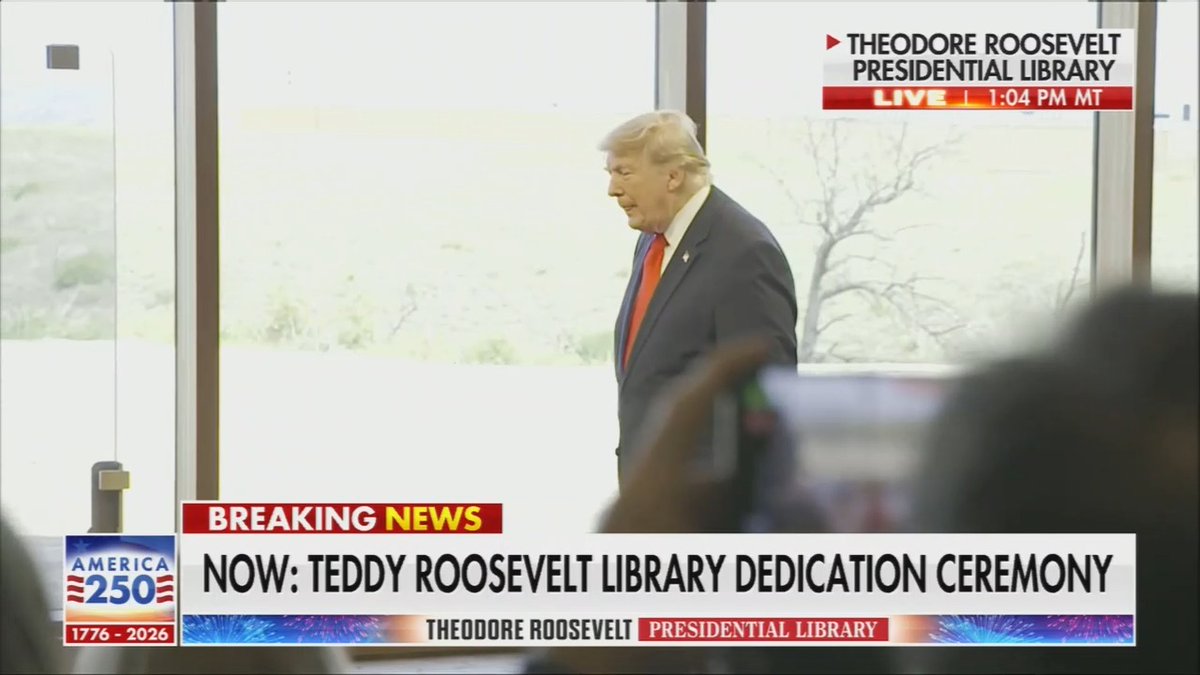 A very confused Trump tries and fails to put a pair of giant scissors into his suit jacket