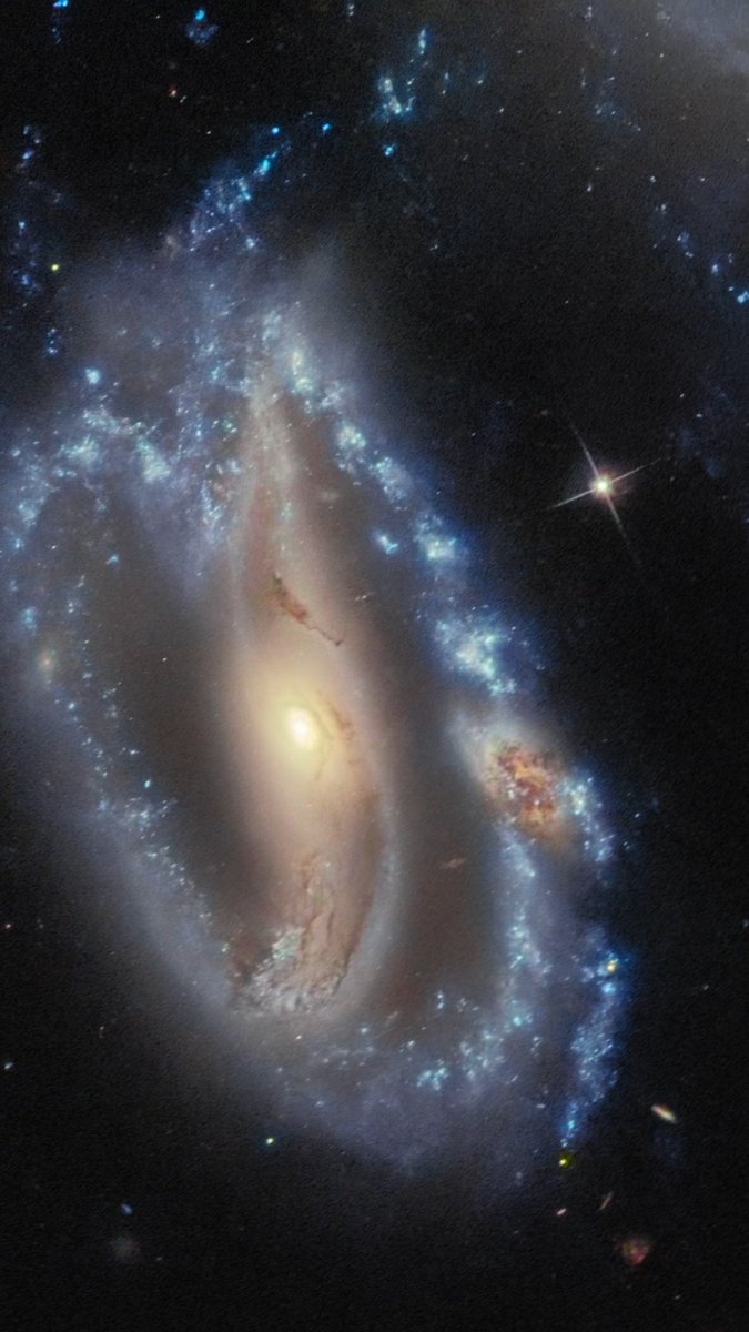 Can you spot the hidden galaxy? The bright blue spiral arm of one galaxy appears to contain a dusty orange patch that is in fact an entire galaxy in itself, according to Hubble’s velocity data. Eventually all three may merge to form a single galaxy. Credit: NASA, ESA.