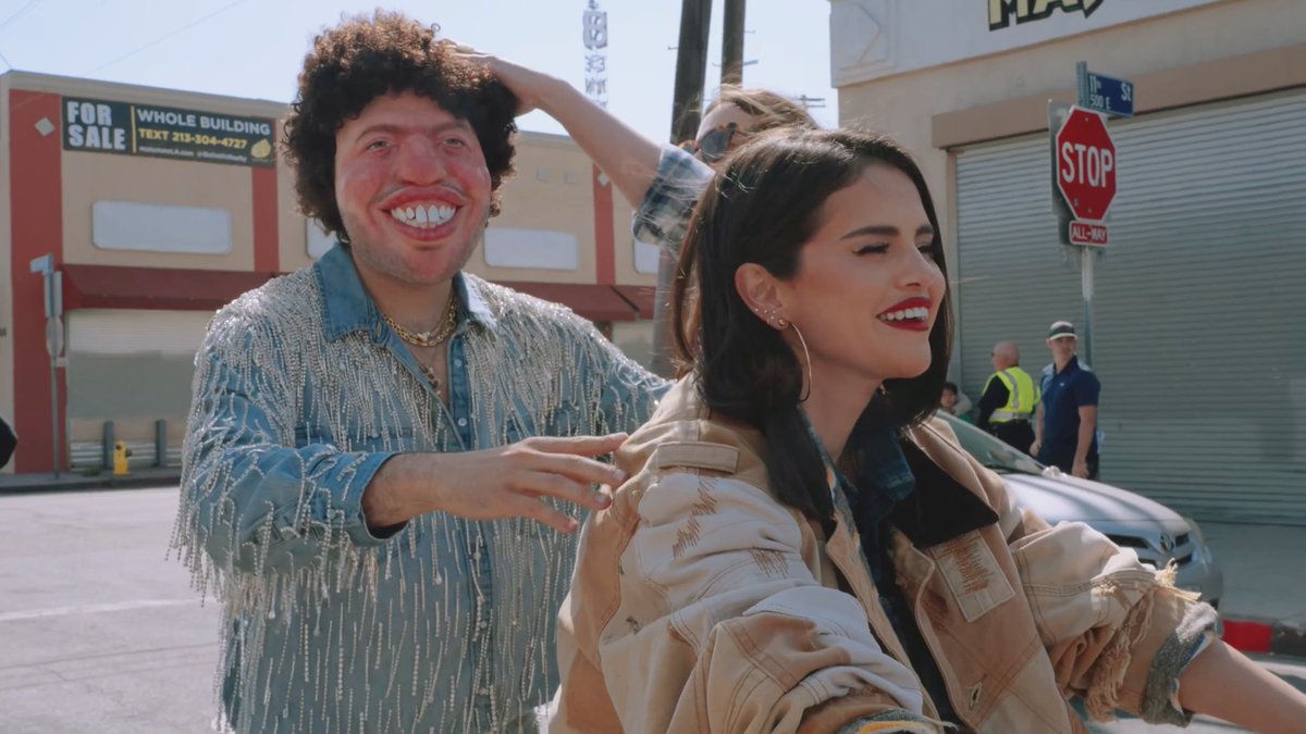 benny blanco attempts to get on the back of Selena Gomez’s bike while wearing his ‘Hermoso’ mask in behind-the-scenes footage from the ‘Te Olvido (La La)’ music video.