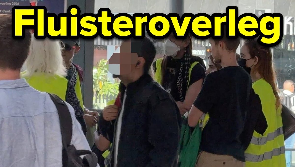 Fluisterend overleg voorafgaand aan de 'Stille Sit-in'. Op Utrecht CS stemt de organisatie in alle stilte de laatste instructies af met de ordehandhavers in gele hesjes. Opvallende aanwezige vanavond: een bekend gezicht uit de Utrechtse politiek. Ziet u wie?