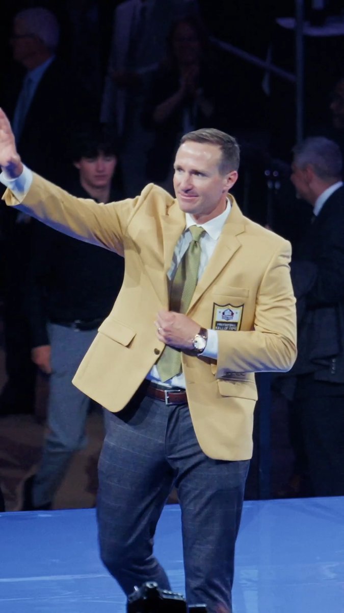 Drew Brees walking amongst the Pro Football Hall of Fame Legends