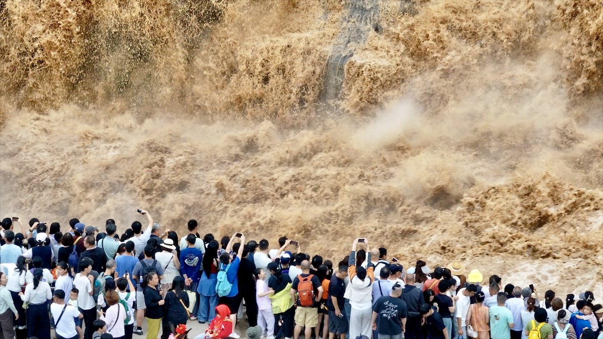 Hukou Waterfall on the Yellow River in north China is seeing a summer holiday tourism surge, attracting an average of 13,000 visitors a day. Recent rainfall upstream has increased the river's sediment load, creating its iconic golden-yellow cascade.