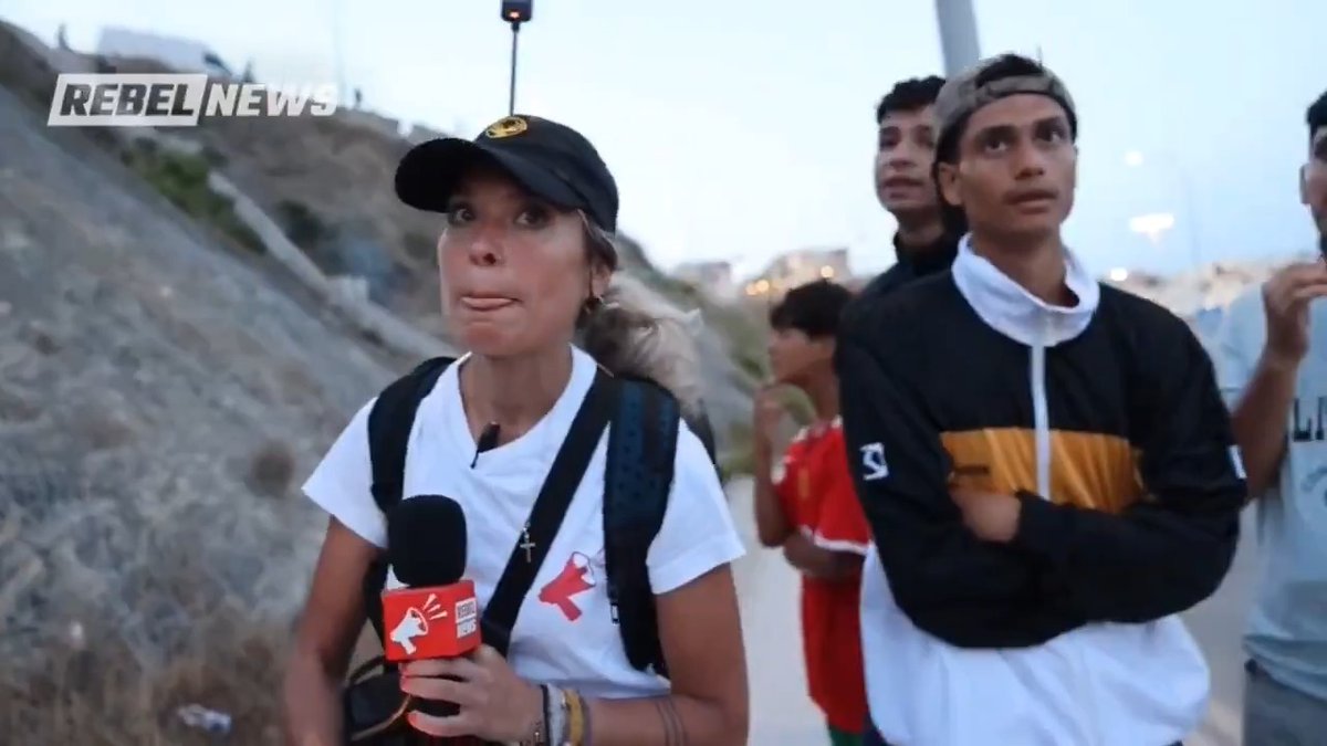 ROCK THROWN AT REPORTER While Investigating Ceuta Migrant Crisis Efrain Flores Monsanto and Alexa Lavoie report from Ceuta, where Spain's new floating sea barrier has failed to stop migrants swimming, climbing and wading into the enclave, and where a rock was thrown at our reporter mid-interview. Rebel News reporters Efrain Flores Monsanto and Alexa Lavoie recently travelled to Ceuta to report on the recent mass illegal crossings into Spain's two North African enclaves, Ceuta and Melilla. Spanish authorities have installed a new floating barrier along Ceuta's coastal border, meant to stop people from swimming into Spanish territory from Morocco. But migrants are still climbing fences, crossing by land and wading through the water, raising questions about whether the new defences do anything. The reporters also went into El Príncipe, one of Ceuta's most dangerous neighbourhoods, where residents say people have been assaulted, robbed and killed. It is also where migrants shelter in the bushes and hills surrounding the district, and that is what our reporters found. Migrants are living in the area, and some locals bring them water and other basic necessities. Along the shoreline, the impact of the crossings is impossible to miss. Parts of the beach have been cleaned. Long stretches have not. Piles of garbage, makeshift tunnels and bedding left near the ferry terminal show the strain on the city. One visitor told Rebel News he was shocked to see new arrivals sleeping in the grass shortly after reaching Spanish soil. At night the risks grow. Hotel workers told Rebel News that new arrivals are no longer concentrated in one spot but are now scattered across the city. During an interview with a group of illegal migrants, someone threw a rock at Lavoie, forcing the crew to leave. Some of those who crossed said they came for a better life and hoped, with God's help, to support their parents. One of them said, "We keep our stuff clean," while the ground around him was covered in garbage. This is a small preview of a much larger report coming soon.