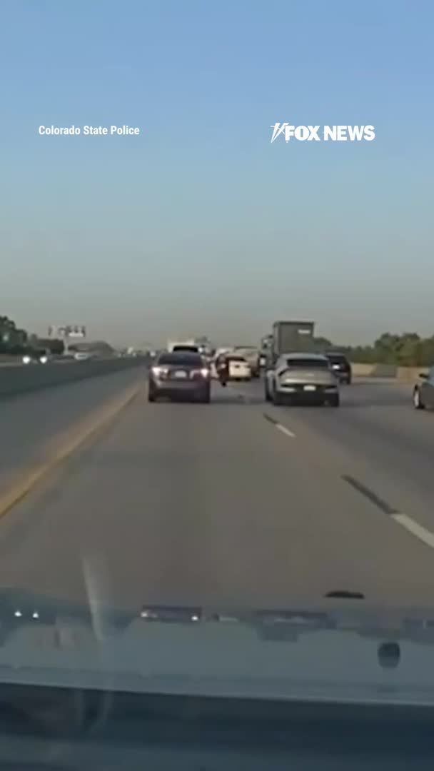 A motorcycle rider weaving between traffic slams into the back of a white sedan as it changes lanes on I-76 in Denver, with Colorado State Patrol vehicles driving right behind. Colorado State Patrol says the rider was lane splitting, which is illegal in Colorado when traffic is moving. The rider’s condition and any injuries were not reported.