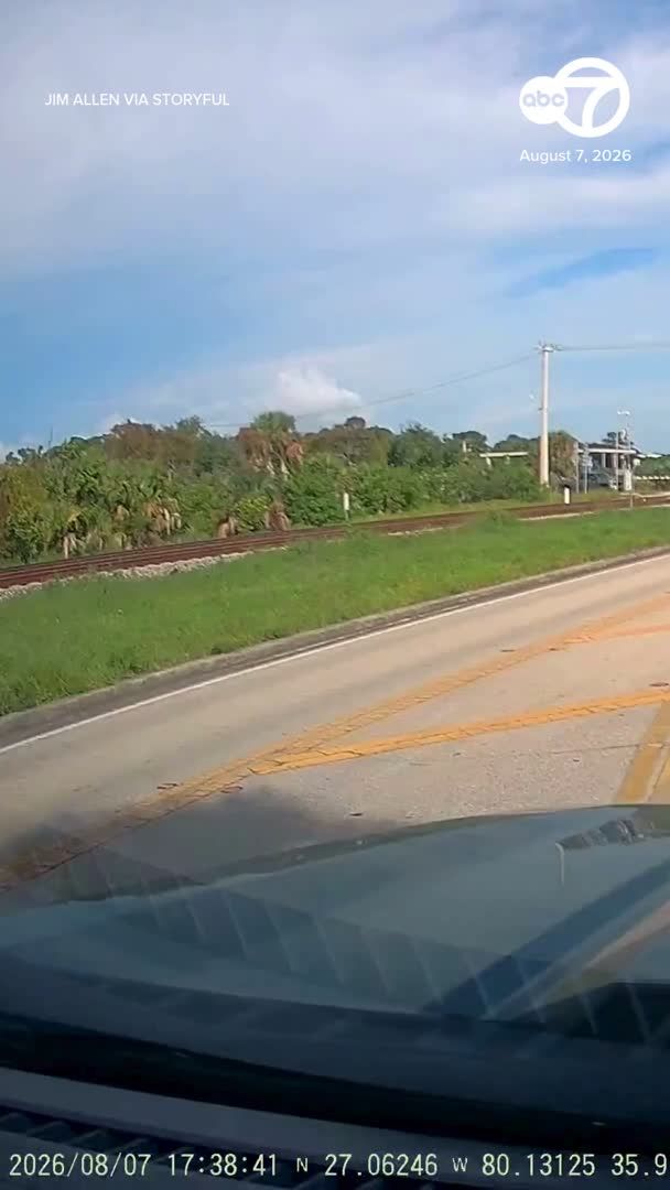 A man sprinted across railroad tracks in Florida to rescue a woman whose car was stuck beneath a crossing arm as an oncoming train barreled toward her vehicle.