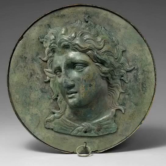El Espejo de caja de bronce con el dios Pan es una delicada y representativa pieza de la metalurgia de la Antigua Grecia, datada a finales del siglo IV a.C. Se exhibe permanentemente en la galería 158 de The Metropolitan Museum of Art de Nueva York. A diferencia de los espejos modernos de vidrio recubiertos de plata, los antiguos griegos lograban el reflejo utilizando el propio disco interior de bronce fundido, el cual era pulido minuciosamente hasta obtener un acabado liso y brillante como un espejo reflectante. Las tapas exteriores protegían esta delicada zona pulida contra la oxidación y los rayones del uso diario.