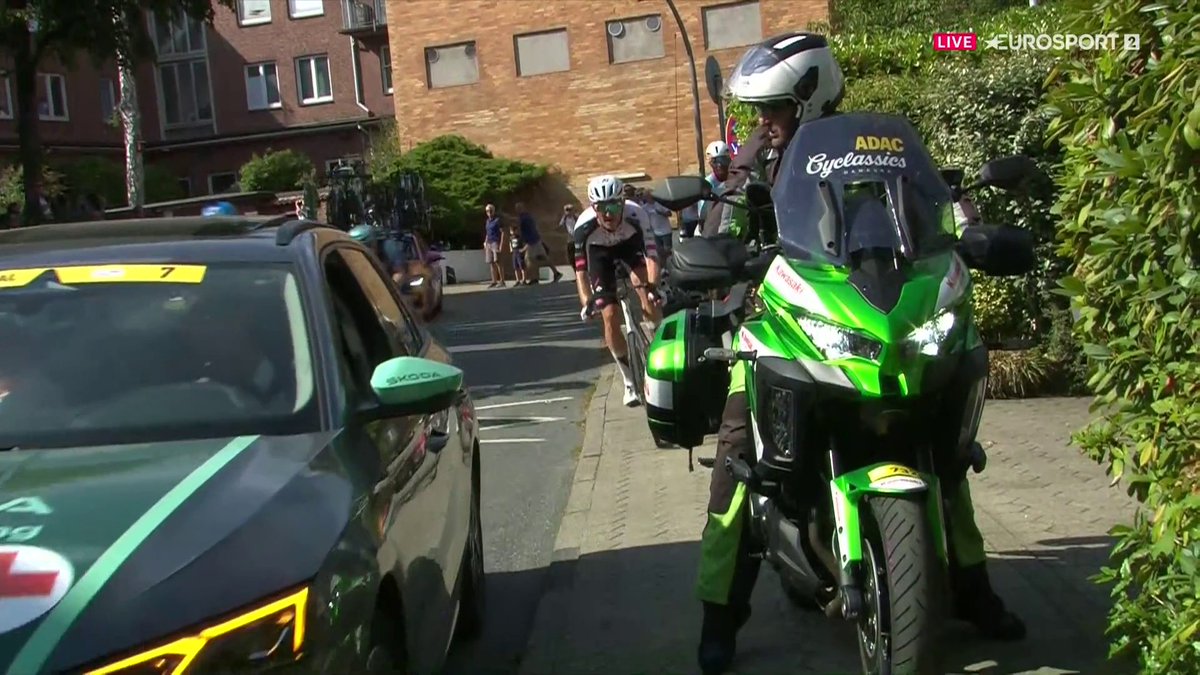 😱 ¿PERO CÓMO SE TE OCURRE PARAR AHÍ? Caída de Grmay y el coche médico se frena en plena salida de curva. Mikkel Bjerg venía lanzado, se lo encuentra de frente y su reacción, con golpe incluido al coche, lo dice todo. #ADACCyclassics | #LaCasaDelCiclismo