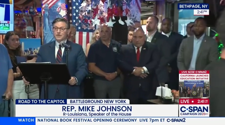 Mike Johnson is interrupted by a waiter during a campaign stop at a restaurant
