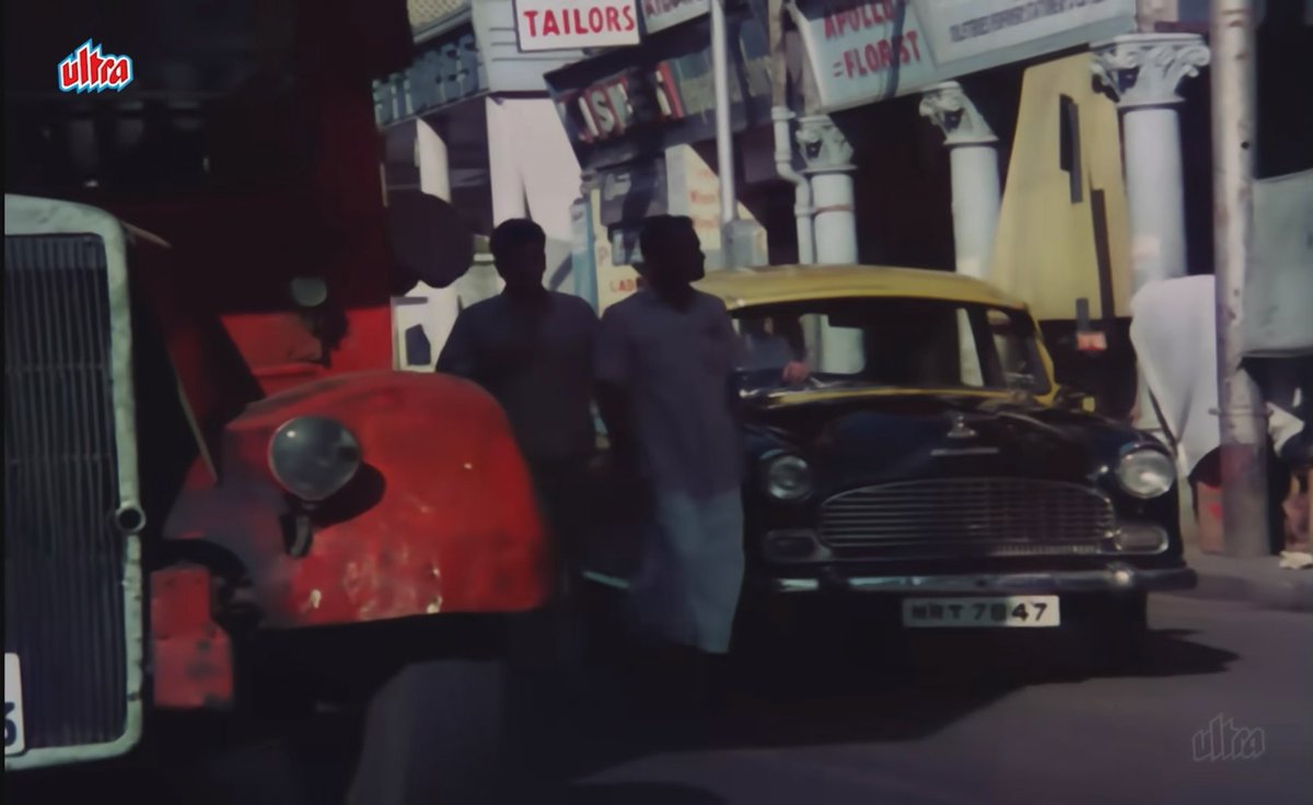 1960s Mumbai: Jeetendra ji, looking for a job on the streets of Colaba. This is Colaba Causeway, decades ago. Look closely: a BEST double-decker, vintage cars, men in crisp white clothes… and did you spot the iconic Leopold Cafe in the frame? A little glimpse of Mumbai that feels like a time machine. #OldMumbai
