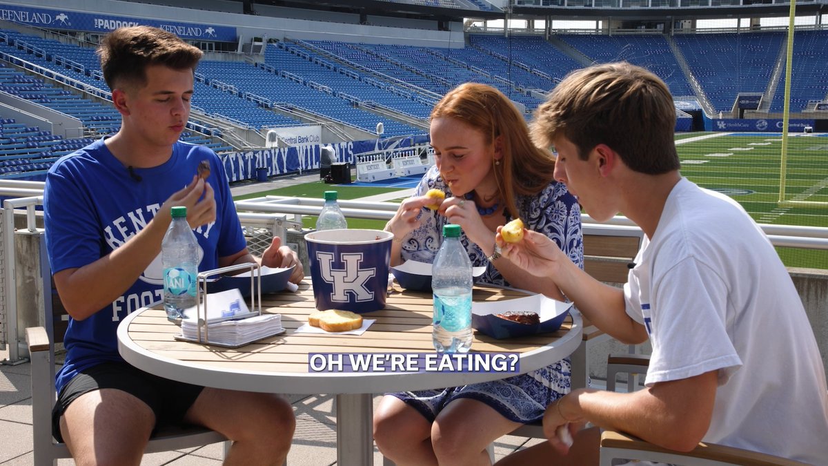 The NEW concession menu at Kroger Field has arrived just in time for Kentucky Football kickoff 😼 Reminder: Kroger Field is now cashless 💳 Kentucky Athletics #KrogerField #KrogerFieldConcessions #KentuckyFootball [Video Description: Three students sit in the stadium at Kroger Field as a chef presents a lineup of new concession foods, including fan favorites and "wow" items. The video captures the students sampling and reviewing dishes like nachos, hot dogs, and the Big Blue Belly Buster.]