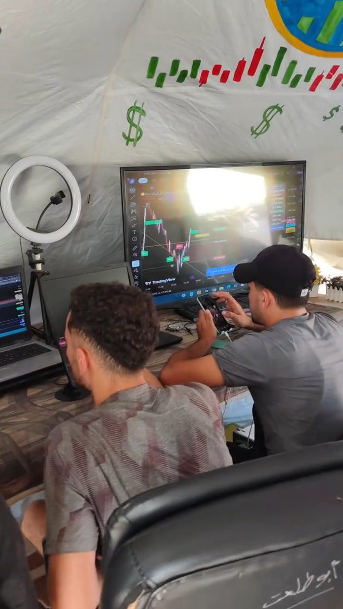 Gaza man opens TRADING TENT in the MIDDLE of BUILDING RUINS MULTIPLE SCREENS display PEOPLE FIXATED on STOCKS as CHARTS swing RED and GREEN