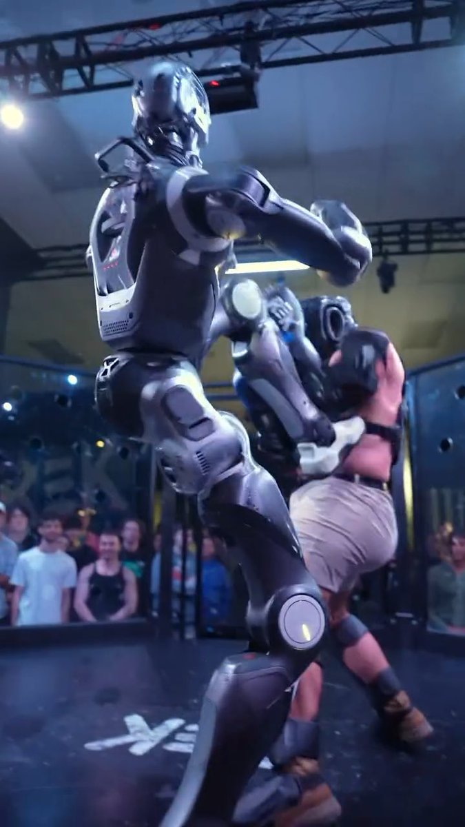FIRST-EVER FIGHT between HUMAN and REAL-LIFE 6 FOOT TERMINATOR Man gets some PUNCHES IN before ROBOT KICKS HIM IN HEAD HUMANOID ROBO STRIKES BACK MOMENTS LATER and SENDS HUMAN ACROSS CAGE