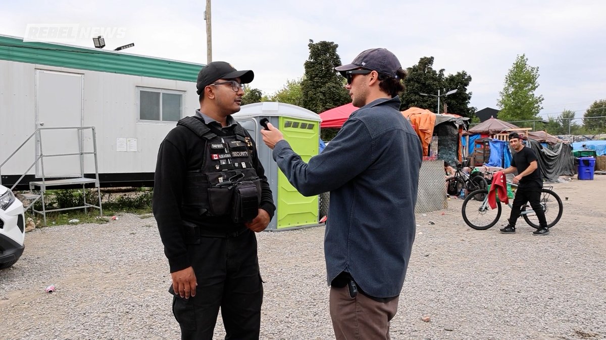 Security stopped us from filming at a Canadian homeless encampment. He told us we couldn't film on-site, only from the sidewalk, claiming the land where the tents sit is private property. This is Kitchener, Ontario.